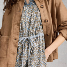 Load image into Gallery viewer, Person wearing a brown jacket over a patterned dress on a plain background