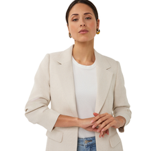 Load image into Gallery viewer, Woman wearing a beige blazer over a white shirt with blue jeans on a white background