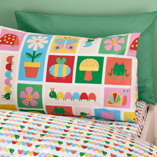 Load image into Gallery viewer, Children's bedding set with colorful patterns on a green pillow and white bedspread.