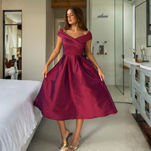 Load image into Gallery viewer, Woman in a burgundy dress standing in a modern bedroom.