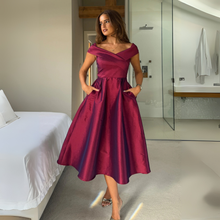 Load image into Gallery viewer, Woman in a burgundy dress standing in a modern bedroom.