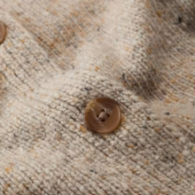 Load image into Gallery viewer, Close-up of a textured cream-colored knit fabric with small brown buttons.