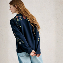 Load image into Gallery viewer, Person wearing a dark blue jacket with floral embroidery on a light background