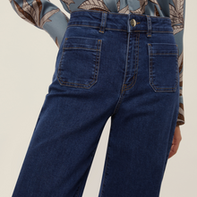 Load image into Gallery viewer, Blue jeans worn by a person on a beige background