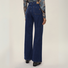 Load image into Gallery viewer, Person wearing blue flared jeans on a plain background