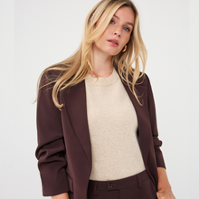 Load image into Gallery viewer, A blonde woman wearing a dark brown blazer over a cream knit sweater and matching dark brown trousers, photographed against a clean light gray studio background.