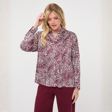 Load image into Gallery viewer, A woman modeling a long-sleeve button-up shirt with a burgundy and white wavy abstract pattern, paired with burgundy pants, against a plain off-white background.