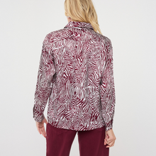 Load image into Gallery viewer, A woman shown from the back wearing a long-sleeve collared button-up shirt with an abstract zebra-like pattern in burgundy and white, paired with burgundy pants, against a plain light gray studio background.