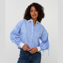 Load image into Gallery viewer, Woman wearing a blue striped shirt with rolled-up sleeves against a white background