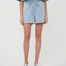 Load image into Gallery viewer, Light blue denim shorts worn by a person on a white background