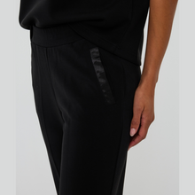 Load image into Gallery viewer, Black pants worn by a person on a light gray background