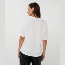 Load image into Gallery viewer, Woman wearing a white t-shirt and black pants on a plain background