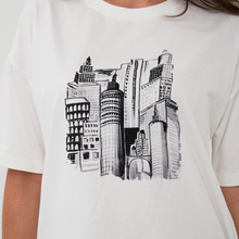 Load image into Gallery viewer, White t-shirt with black cityscape graphic and 'FAKALO' branding