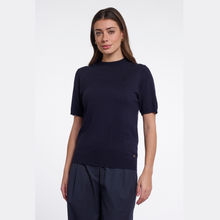 Load image into Gallery viewer, A woman modeling a short-sleeve knit top in dark navy blue, paired with matching navy trousers, against a plain light gray studio background.