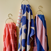 Load image into Gallery viewer, Three colorful throws hanging on a wall with gold hooks.