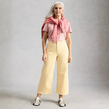 Load image into Gallery viewer, Woman wearing a pink top and beige pants with a pink scarf against a gray background