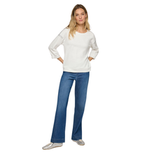 Load image into Gallery viewer, Woman wearing a white long-sleeve top and blue jeans on a white background
