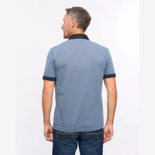 Load image into Gallery viewer, A man viewed from the back wearing a heathered blue short-sleeve polo shirt with dark navy collar and sleeve trim, paired with dark blue jeans against a plain white background.