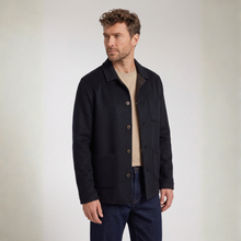 Load image into Gallery viewer, A man wearing a dark navy overshirt jacket over a beige t-shirt and dark blue jeans, standing against a neutral light gray background.