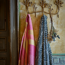 Load image into Gallery viewer, Two throws hanging on a decorative metal hook against a textured wall.