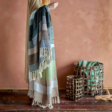 Load image into Gallery viewer, Person holding a plaid blanket with wicker baskets in the background