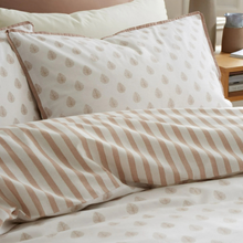 Load image into Gallery viewer, A close-up of a bed dressed in a cream bedding set with a repeating beige leaf pattern on the pillowcases and sheets, and beige vertical stripes on the duvet cover.
