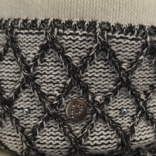 Load image into Gallery viewer, Close-up of a knitted clutch or wallet featuring a black and white textured pattern with a central metallic button and two silver studs.