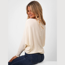 Load image into Gallery viewer, Woman wearing a cream-colored cardigan with pearl buttons on a white background