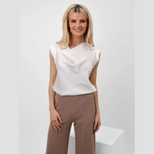 Load image into Gallery viewer, Woman wearing a white sleeveless top and brown pants on a light gray background