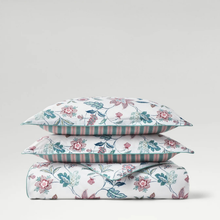 Load image into Gallery viewer, Two stacked pillows and matching folded bedding set with a white background and a delicate floral vine pattern in pink, teal, and muted green, with striped borders.