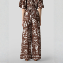 Load image into Gallery viewer, Brown patterned jumpsuit worn by a person on a light gray background
