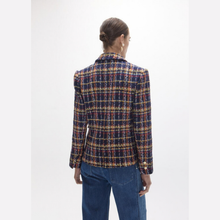 Load image into Gallery viewer, A woman viewed from the back wearing a structured tweed blazer with a multicolor plaid pattern in navy, red, and gold, paired with blue jeans against a plain white studio background.