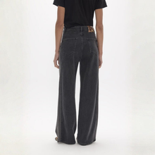 Load image into Gallery viewer, A person shown from the back wearing dark charcoal wide-leg jeans and a black t-shirt against a plain white studio background.