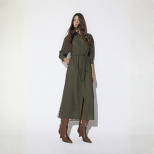 Load image into Gallery viewer, A woman modeling an olive green long-sleeve midi dress with a tie waist and side cutout, paired with brown pointed-toe heeled boots, against a plain white studio background.