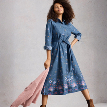 Load image into Gallery viewer, Woman wearing a blue floral dress holding a pink cardigan against a gray background