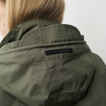 Load image into Gallery viewer, Close-up of a person wearing a green jacket with a brand logo on a white background