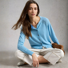 Load image into Gallery viewer, Lady wearing a blue cardigan with light trousers seated