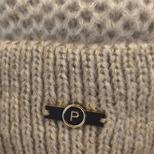 Load image into Gallery viewer, Close-up of a beige ribbed knit sweater with a black and gold personalized name tag pin featuring the letter 'P'.