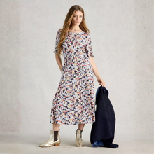 Load image into Gallery viewer, Woman wearing a patterned dress holding a dark jacket against a plain background