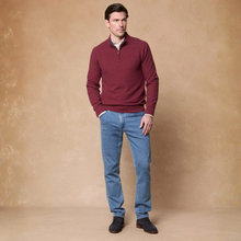 Load image into Gallery viewer, A man modeling a burgundy quarter-zip knit sweater over a light-colored collared shirt, paired with blue jeans and dark brown shoes, standing against a textured beige studio backdrop.