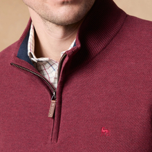 Load image into Gallery viewer, Close-up of a man wearing a burgundy ribbed knit quarter-zip sweater with a small pink embroidered logo on the chest, layered over a plaid collared shirt.