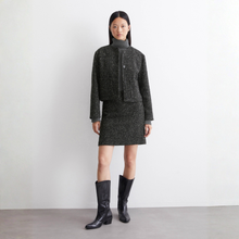 Load image into Gallery viewer, Woman wearing a dark gray outfit with a jacket and skirt, standing against a plain background.