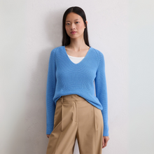 Load image into Gallery viewer, Woman wearing a blue sweater and beige pants against a plain background