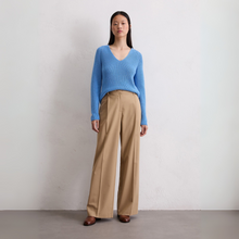 Load image into Gallery viewer, Woman wearing a blue sweater and beige pants against a plain background