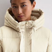 Load image into Gallery viewer, Person wearing a beige puffer jacket with a hood against a plain background