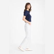 Load image into Gallery viewer, Woman wearing a navy shirt and white pants on a white background