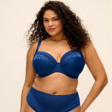 Load image into Gallery viewer, A woman modeling a matching royal blue lingerie set, featuring a sheer underwire bra with lace trim and coordinating high-waisted briefs, against a solid light beige background.