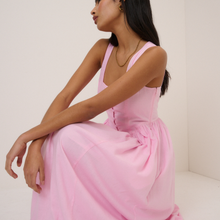 Load image into Gallery viewer, Woman wearing a pink dress sitting against a plain background