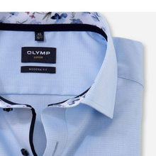 Load image into Gallery viewer, Close-up of a light blue textured dress shirt collar with a black button, showing the fabric weave and patterned lining in the background.