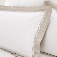 Load image into Gallery viewer, Close-up of beige and white pillowcases with decorative trim on a light background